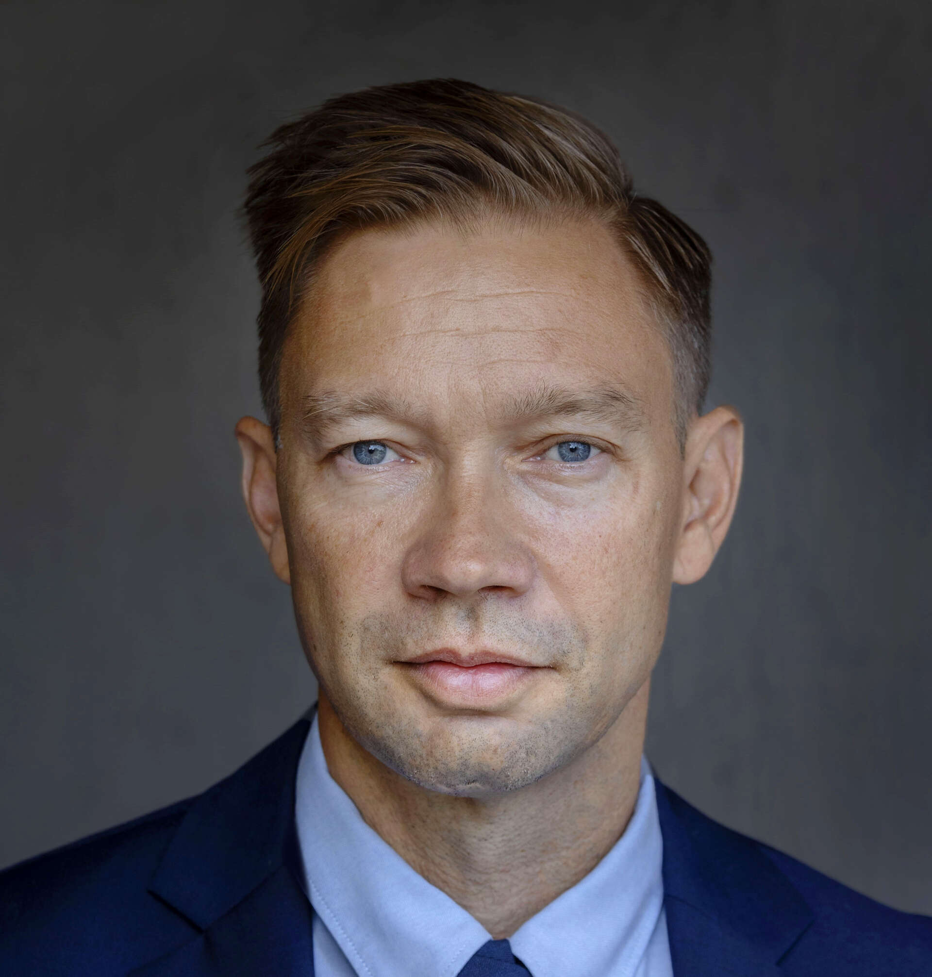 Photo of a man with blue eyes and short hair, wearing a shirt and jacket