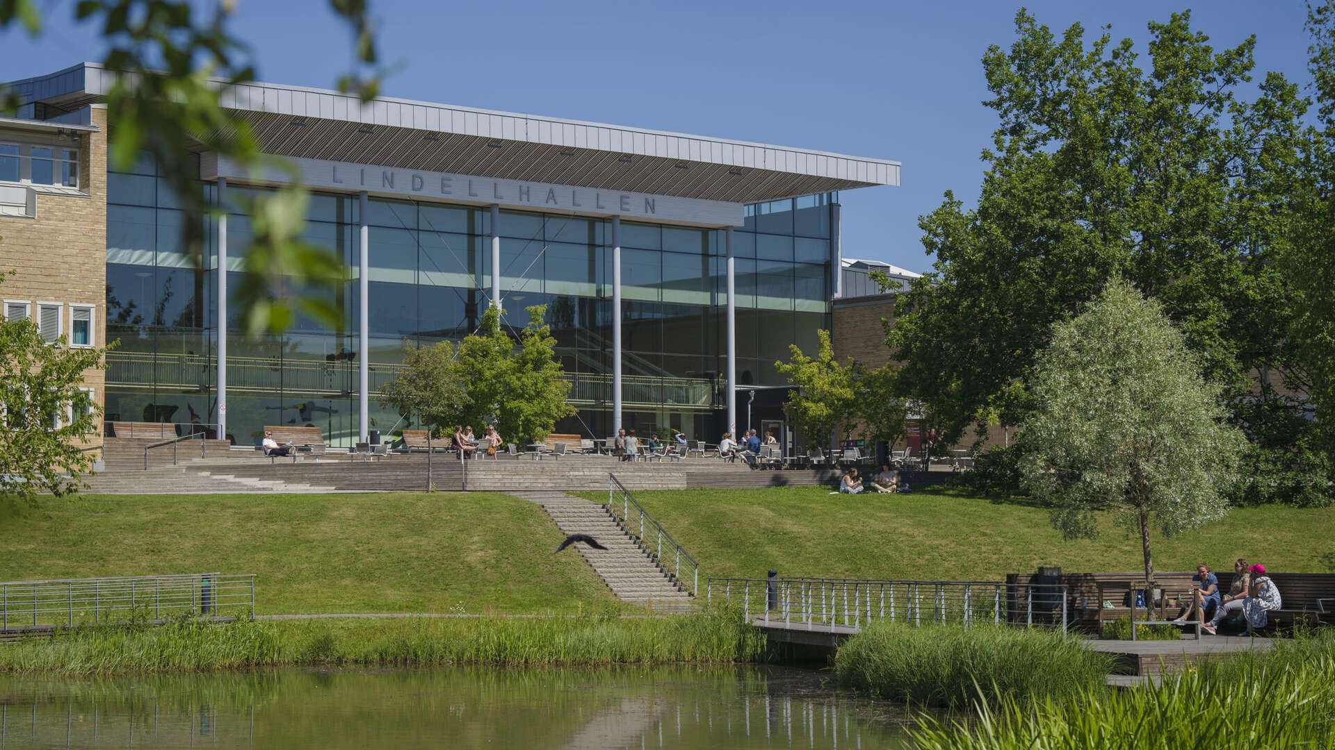 Photo of a large building surrounded by trees, grass and a pond