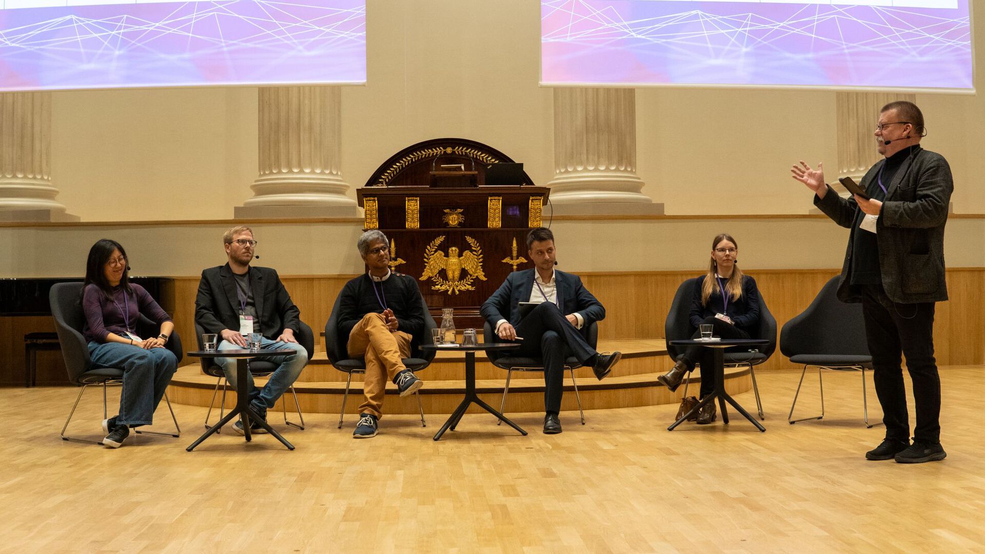 A panel of people sitting in a row. One person standing