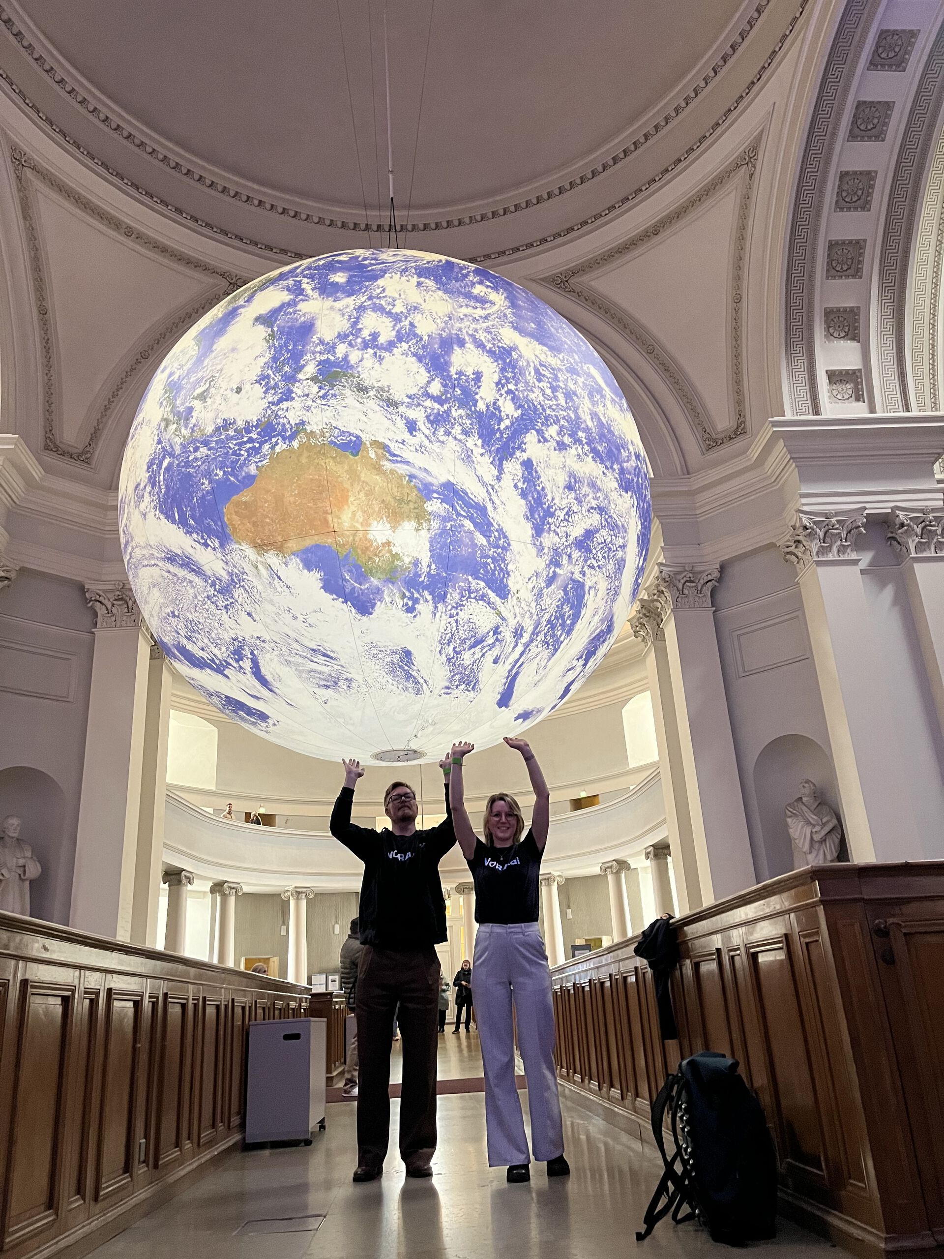 Two NORA staff looking like they are holding up a globe