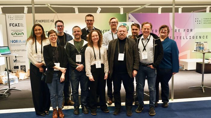 11 people in front of the Nordic booth at EurIPS
