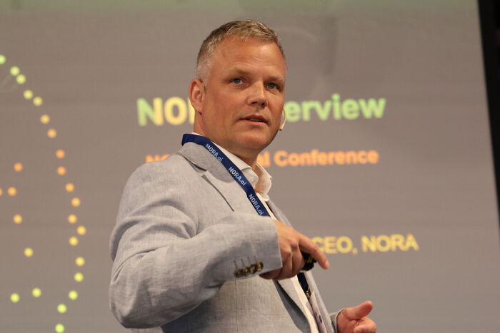 Photo of CEO Klas Pettersen wearing a grey suit in front of a screen