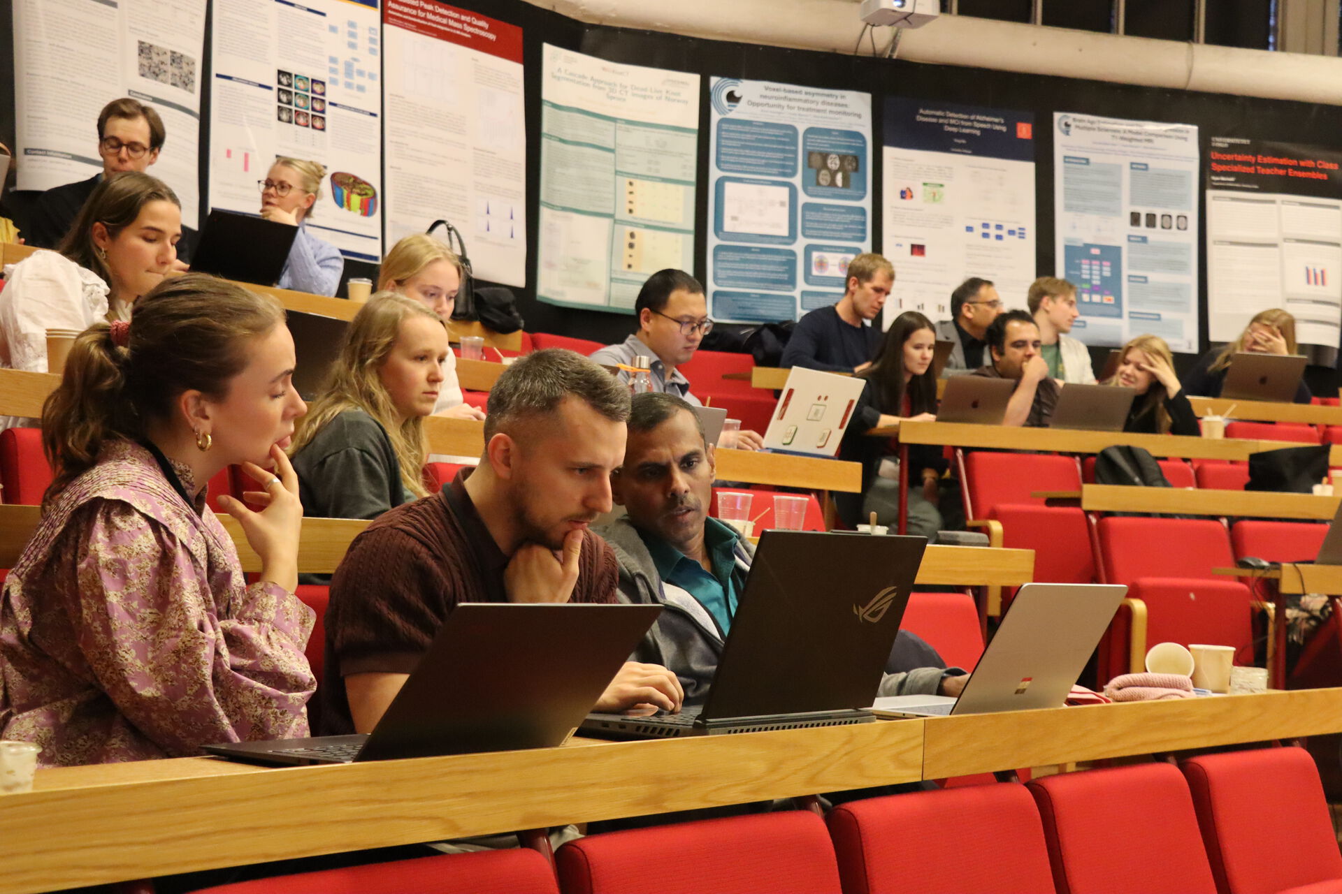 students sitting on rows of benches in a lecture room