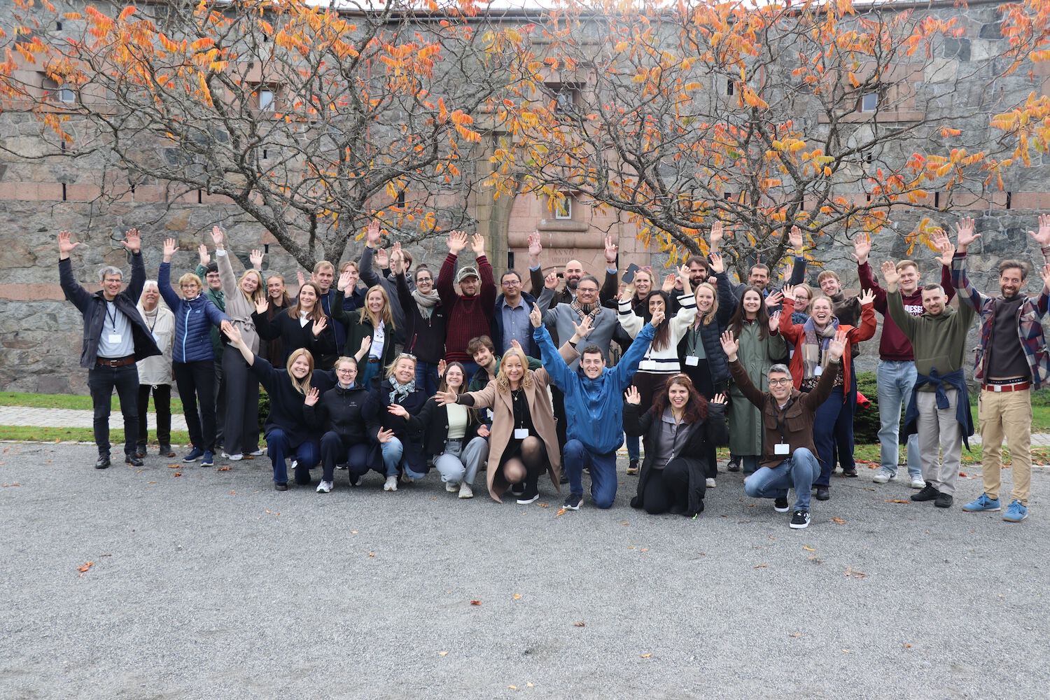 All the PRESIMAL participants gathered, holding their hands up in the air
