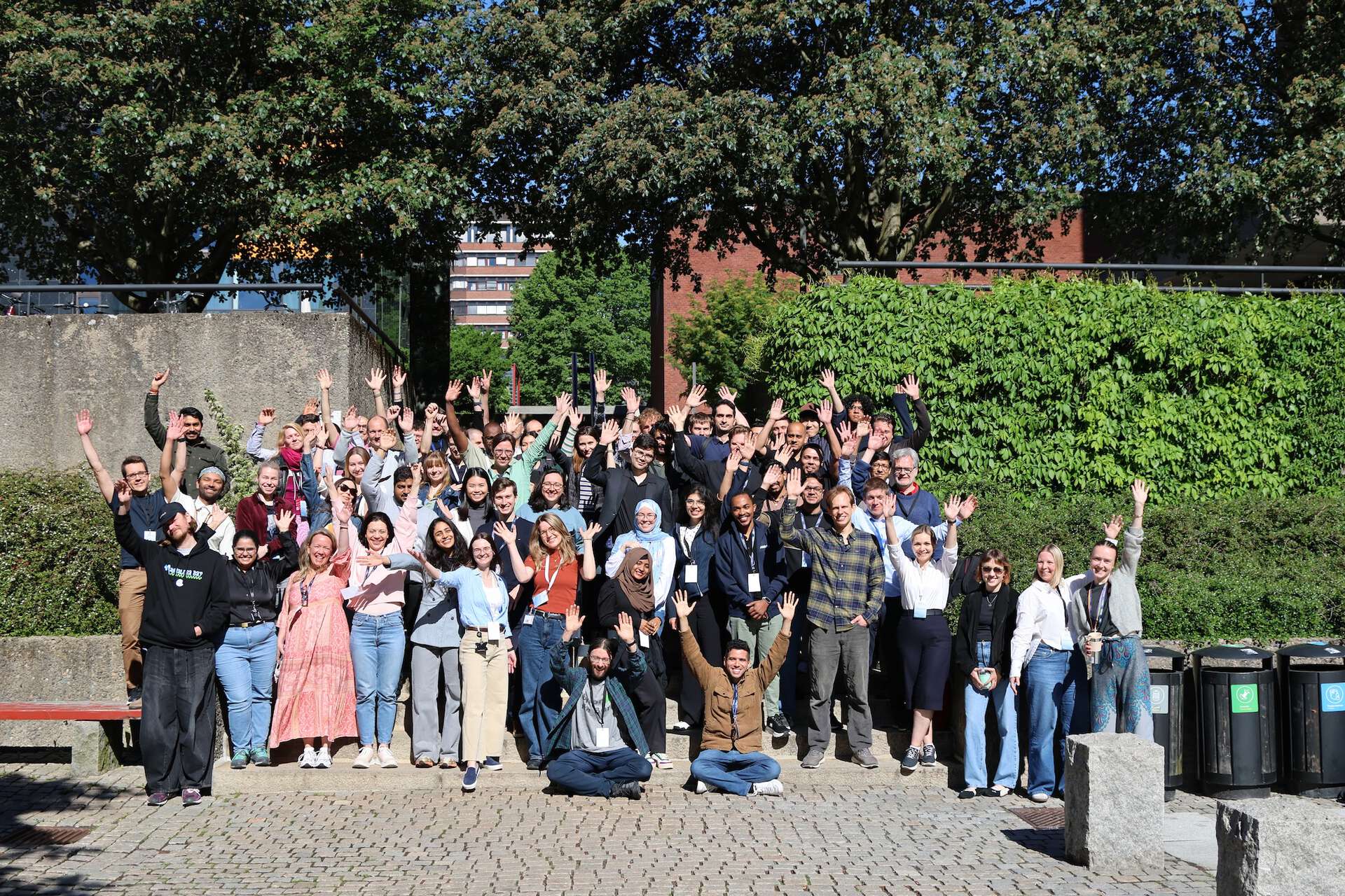 A group of people in the sunshine, holding up their hands