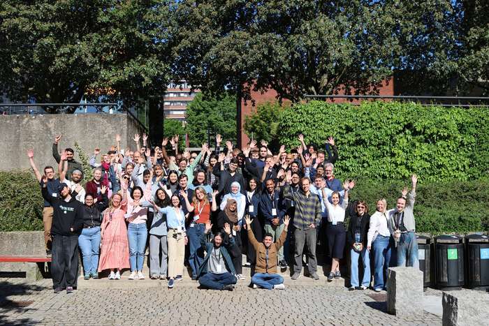 A group of people in the sunshine, holding up their hands