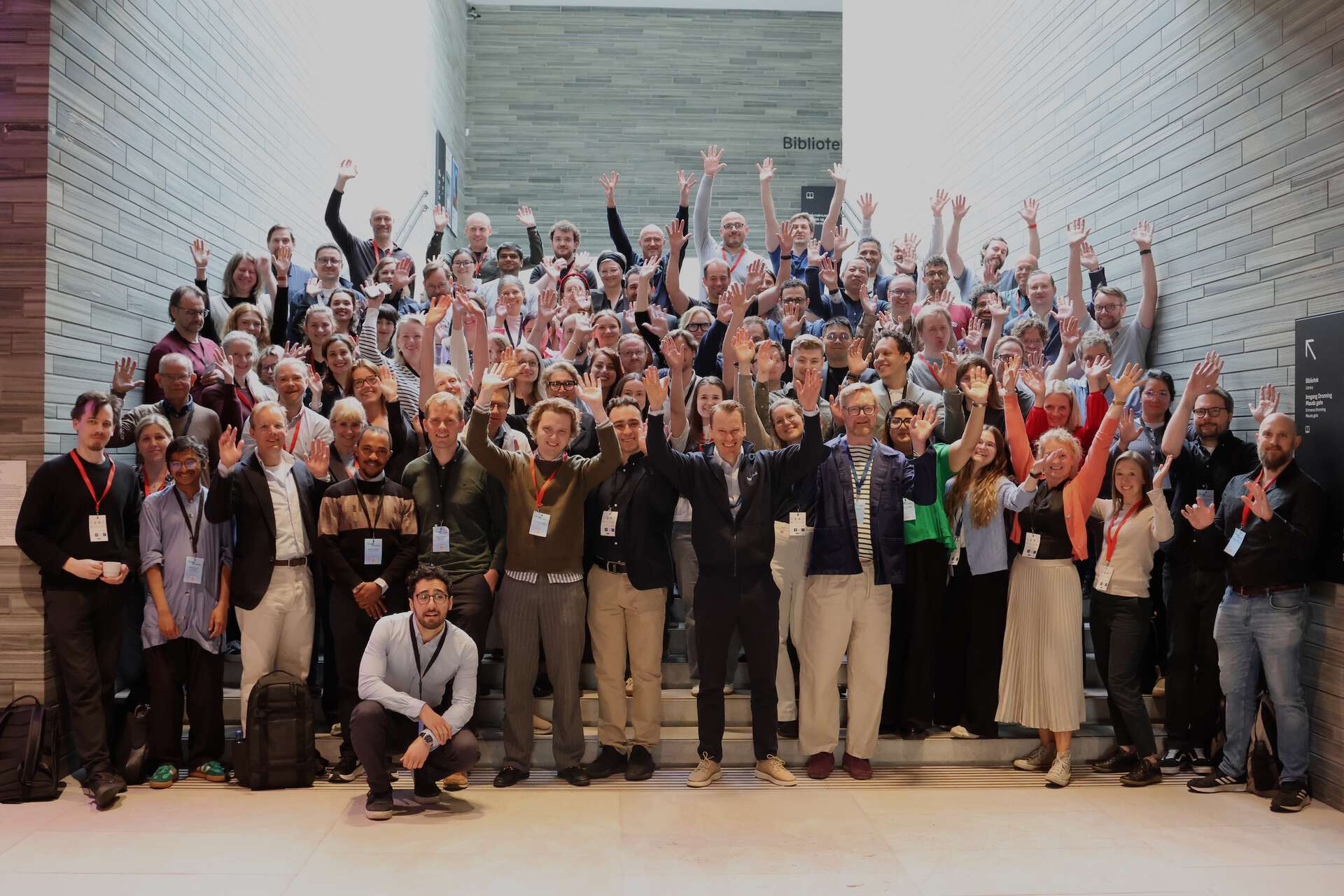 Photo of all the conference participants in the main hall, arms in the air