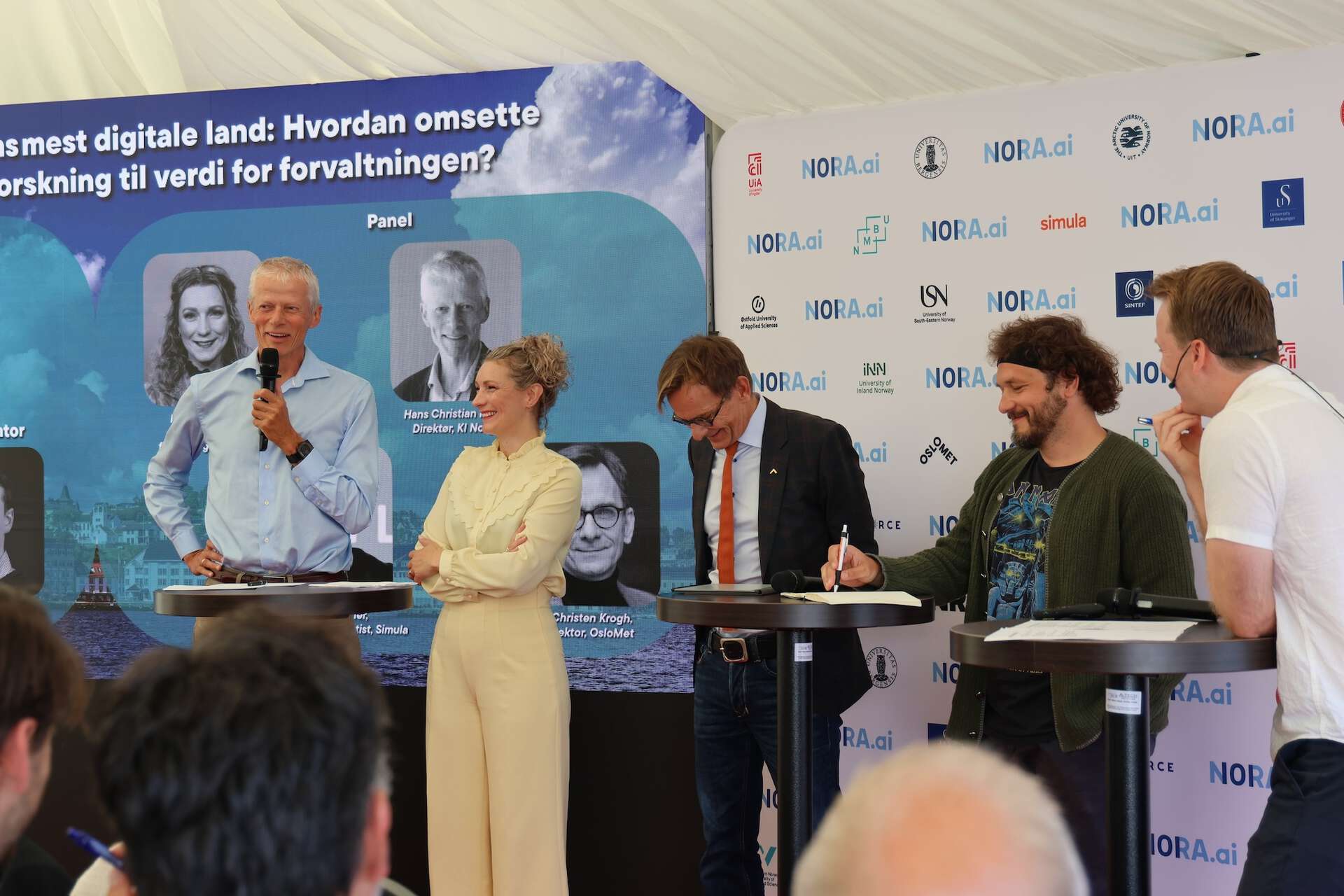 Fem mennesker på scenen, de smiler