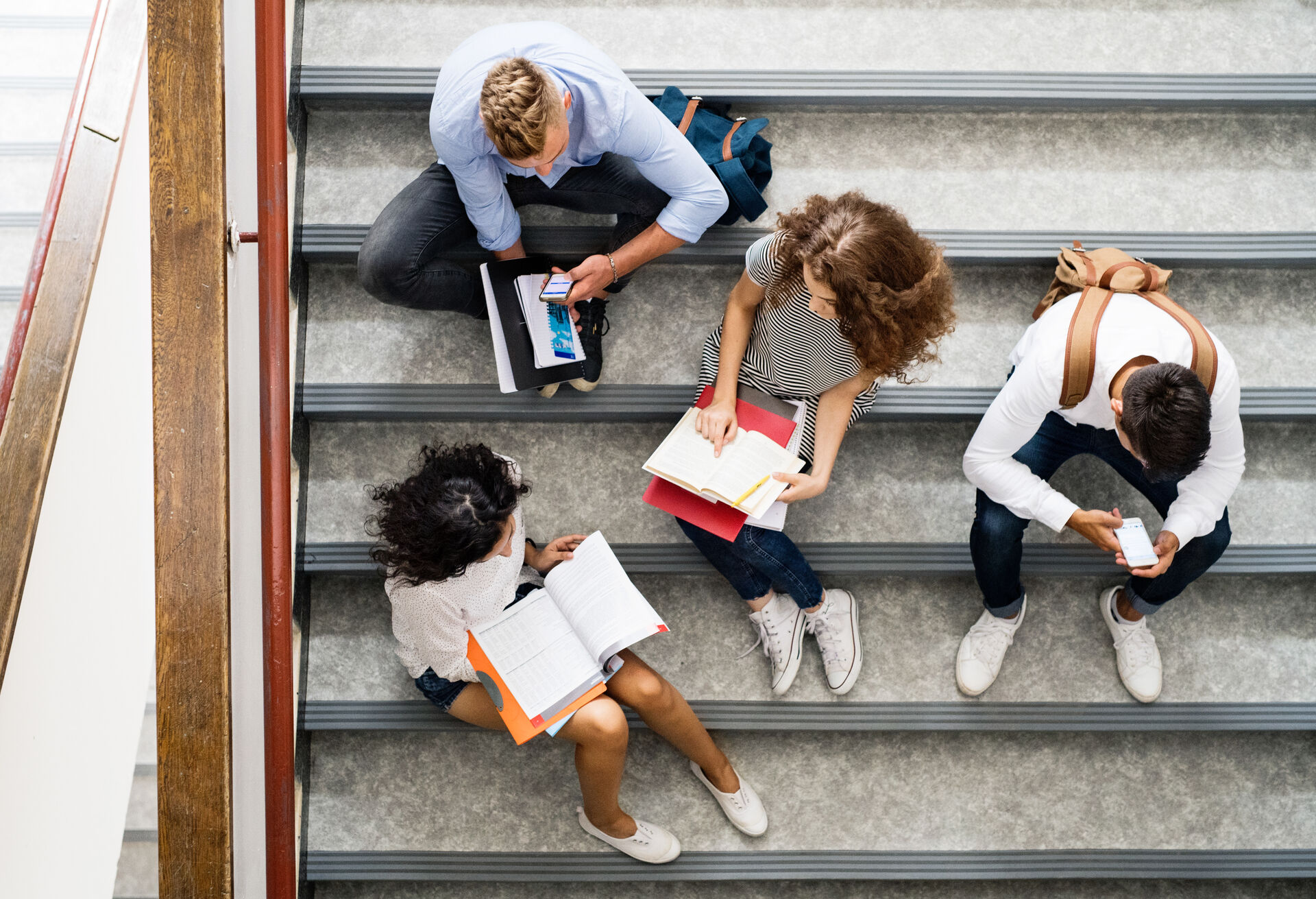 Photo of four students sitting in stairs, photo taken from above