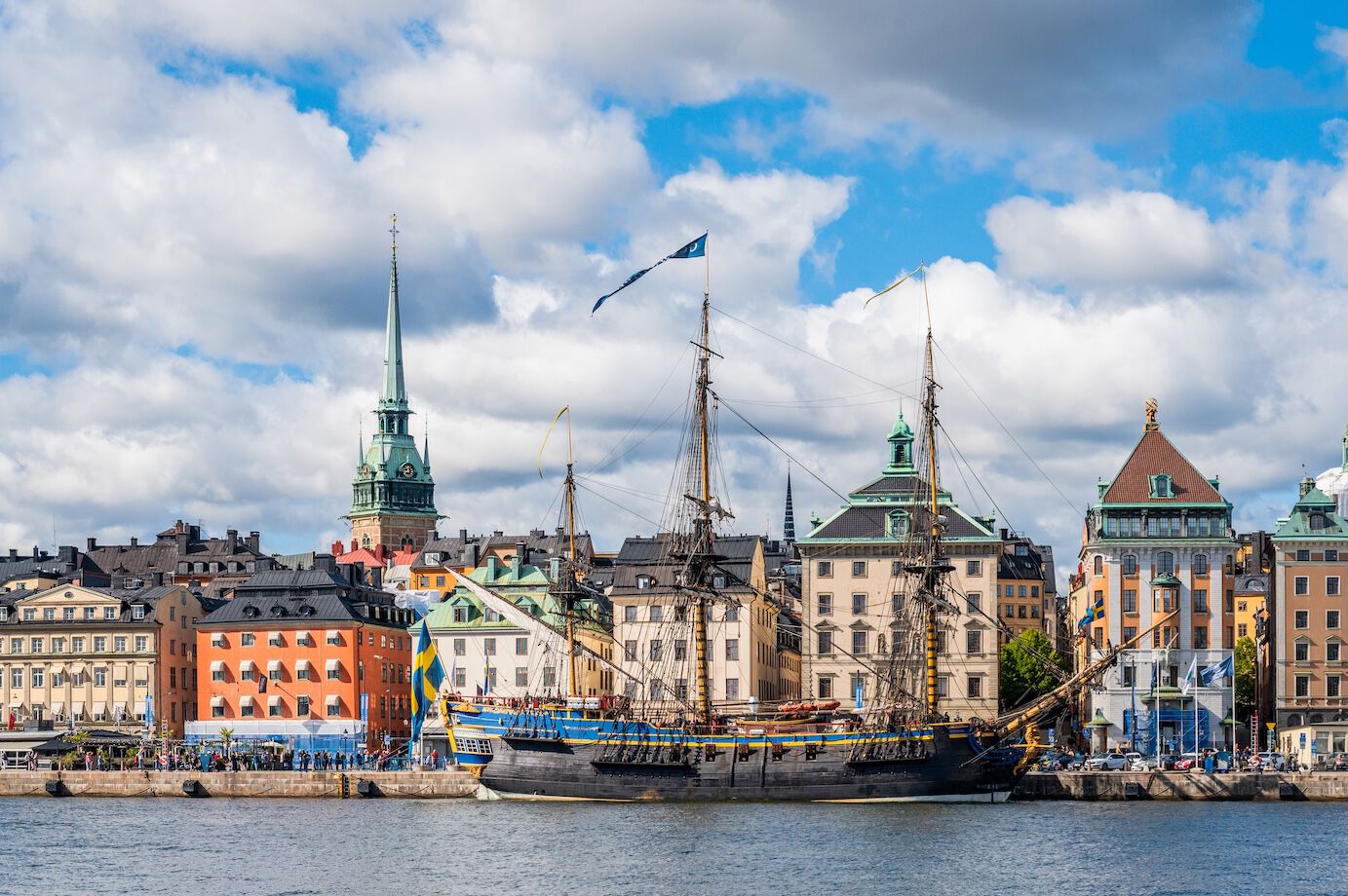 Photo of Stockholm, a wooden ship with a Swedish flag in front of buildings
