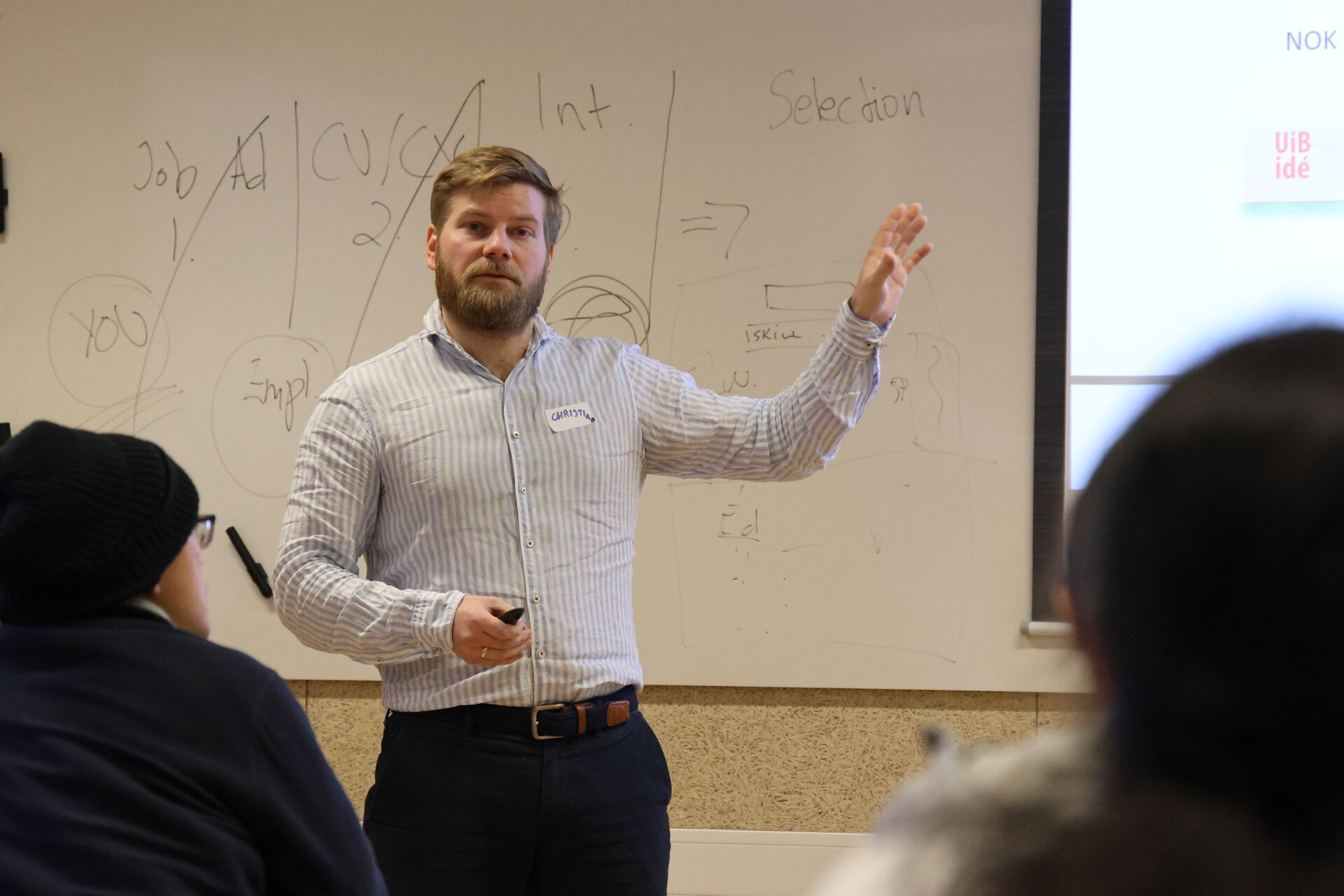 Man in front of a whiteboard, one hand in the air like he is describing something